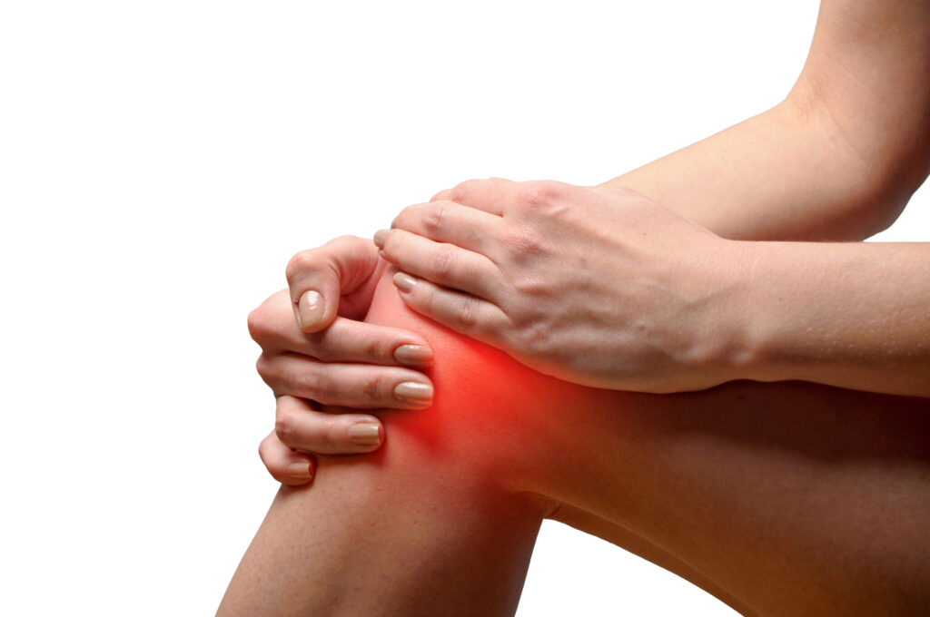 A woman holds her knee. She is experiencing knee pain.