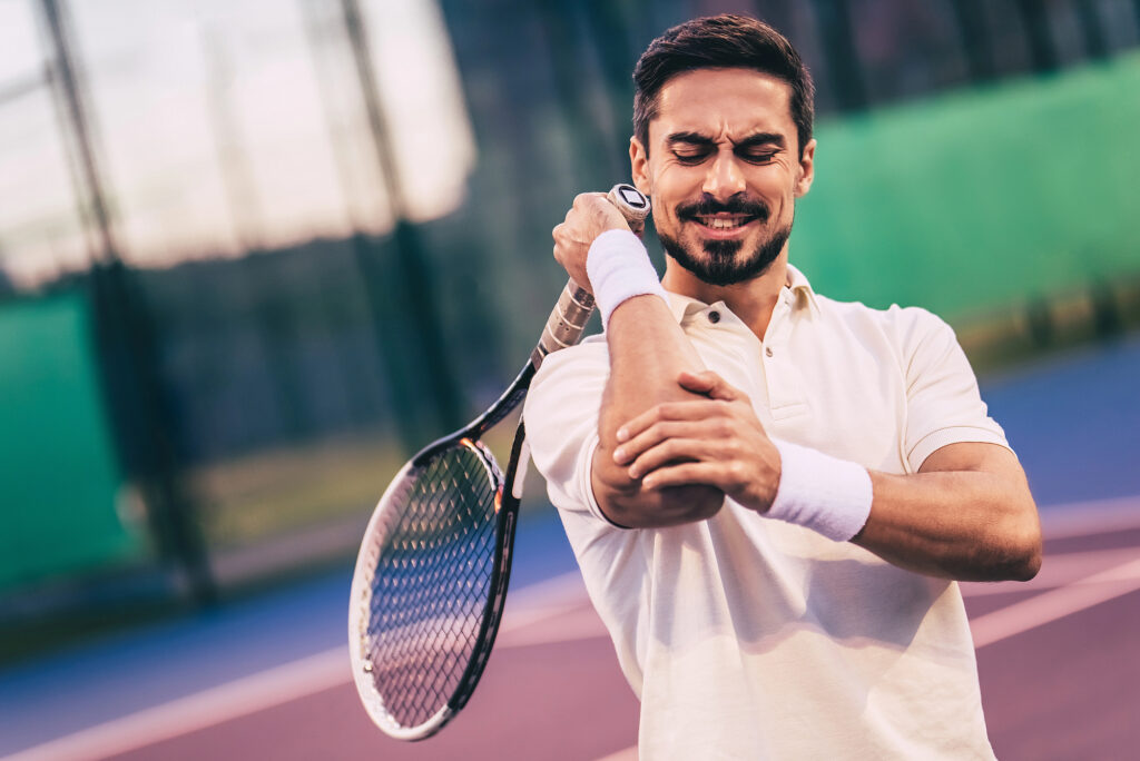 A tennis player holds his right elbow. He has a tennis elbow injury.